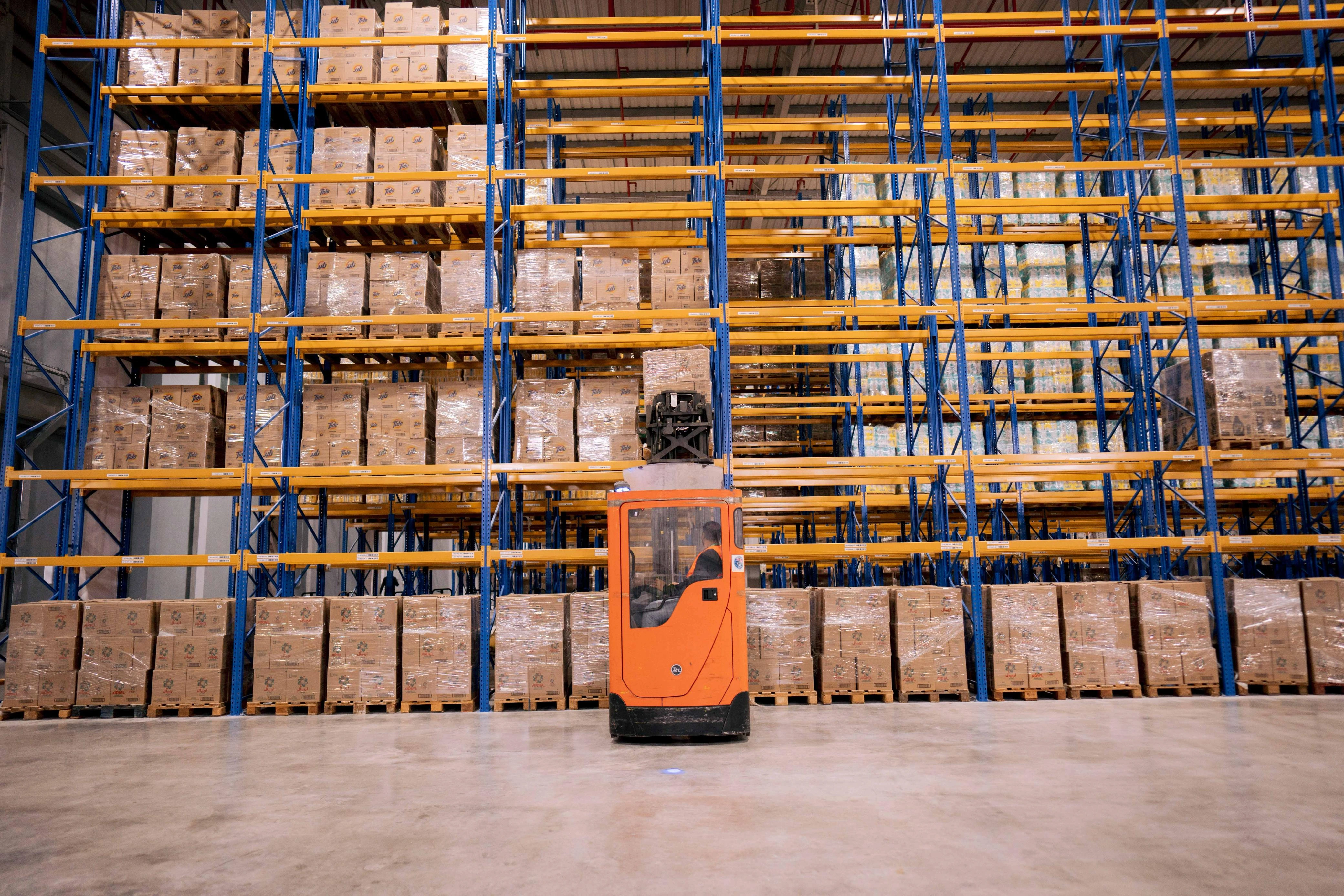 Palletised stock in high-bay racking at an EPx warehouse, with a reach truck working the aisle face